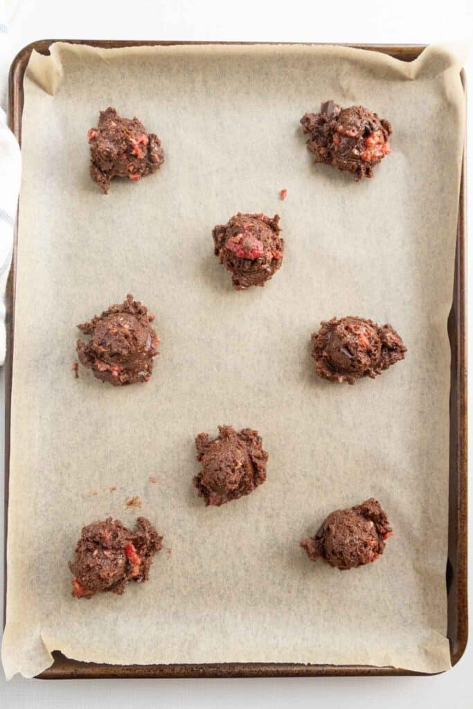 Chocolate cookie dough balls on a baking sheet.