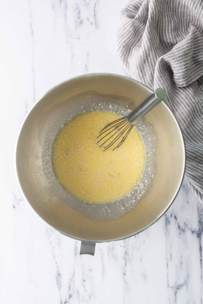 A mixer bowl with yeast, egg, and butter mixed together.