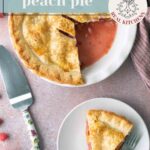A raspberry peach pie with one slice served on a plate, surrounded by fresh peaches and raspberries, with a pie server and a striped napkin.