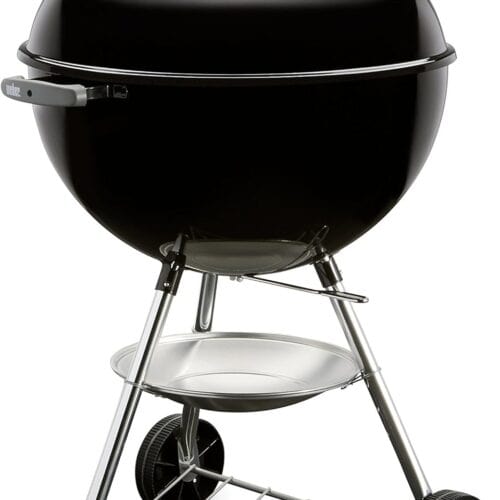 Black kettle-style charcoal grill with a lid, vent, handle, two wheels, and a lower shelf for holding items. The grill stands on three metal legs.