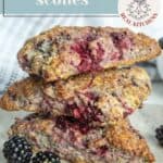 Three triangular blackberry scones are stacked on a surface with fresh blackberries nearby. The text overlay reads “blackberry scones.”.