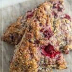 Two triangular blackberry scones rest on parchment paper, showing a golden brown crust with visible blackberry pieces.