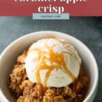 A bowl of caramel apple crisp topped with a scoop of vanilla ice cream and caramel drizzle, with a label reading “caramel apple crisp.”.