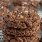 A stack of salted chocolate hazelnut cookies on a cooling rack, with visible sea salt and nut pieces on top.