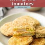A plate of breaded and fried green tomato slices, with one slice cut in half to show the inside.