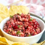 A white bowl filled with cranberry salsa, served with tortilla chips.