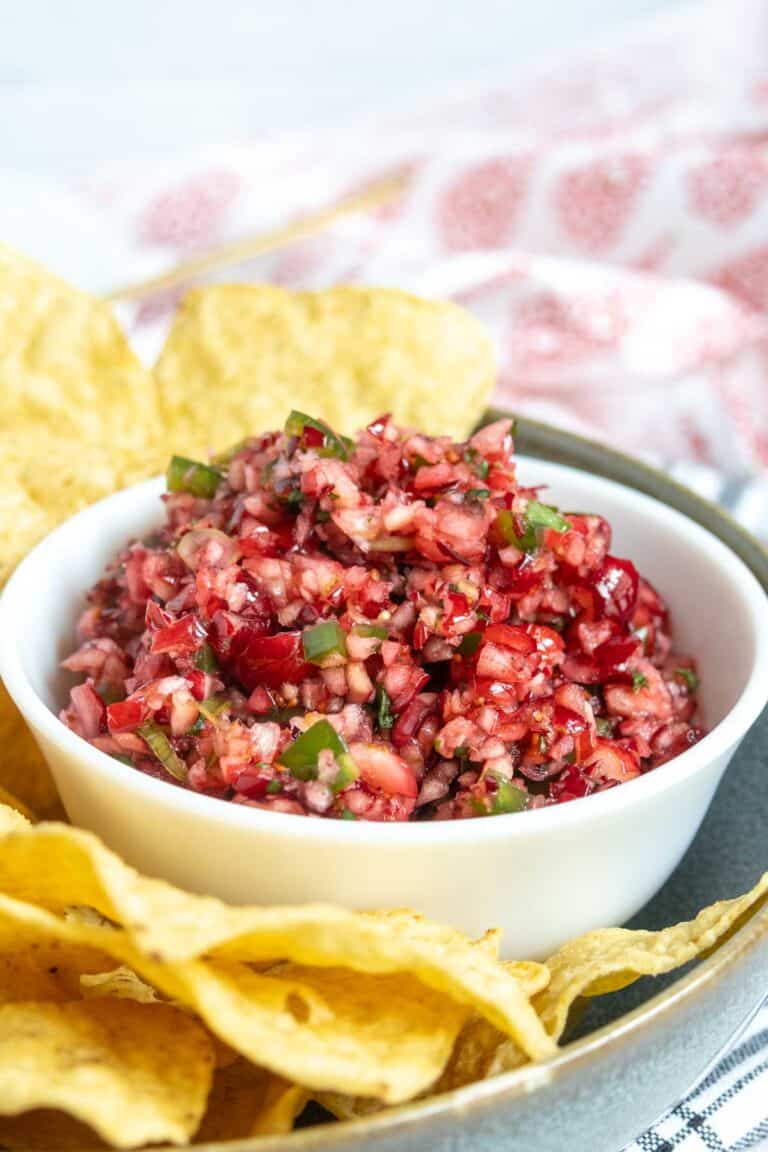 A white bowl filled with cranberry salsa, served with tortilla chips.