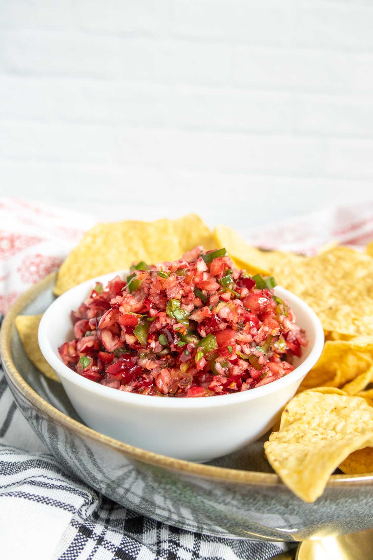 A white bowl of cranberry salsa served with a side of tortilla chips.