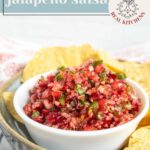 A white bowl of cranberry jalapeño salsa served with tortilla chips, with “cranberry jalapeño salsa” text overlaid.