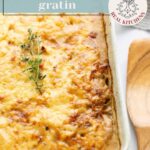 A baked potato gratin with a browned cheese crust, topped with a sprig of thyme in a white ceramic dish. Text overlay reads “caramelized onion potato gratin” and “Real Recipes Real Kitchens.”